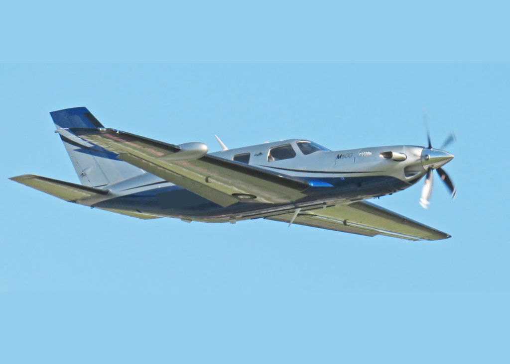 M600 airplane as it is flying, with a blue, clear sky in the background.